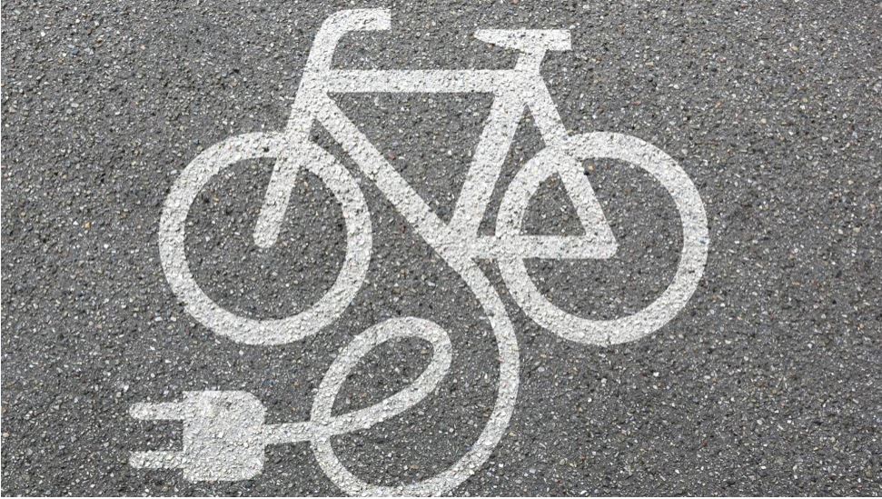 A bicycle and charging-plug symbol painted on a cycleway